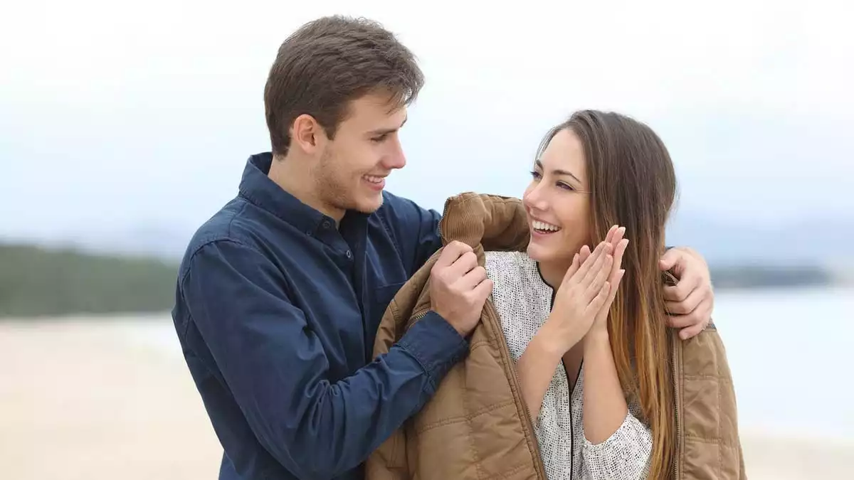 A man putting a coat on his girlfriend