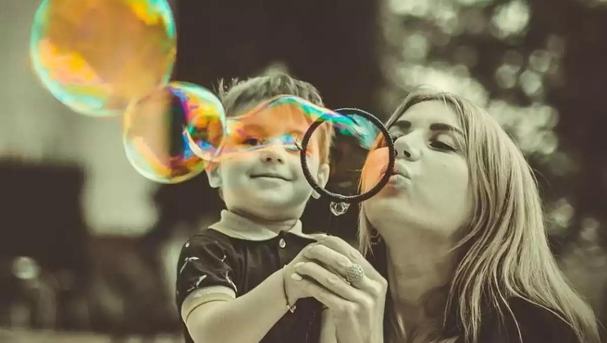 A mother and his son blowing bubbles.