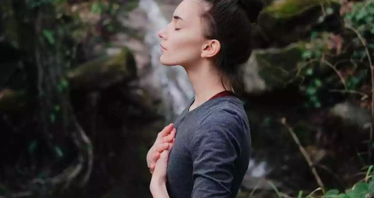 a girl with the eyes closed in the middle of the nature