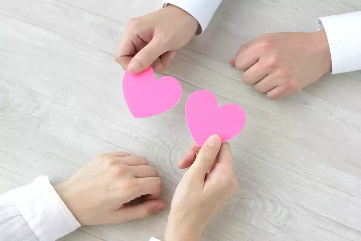 Two people giving each other a paper heart