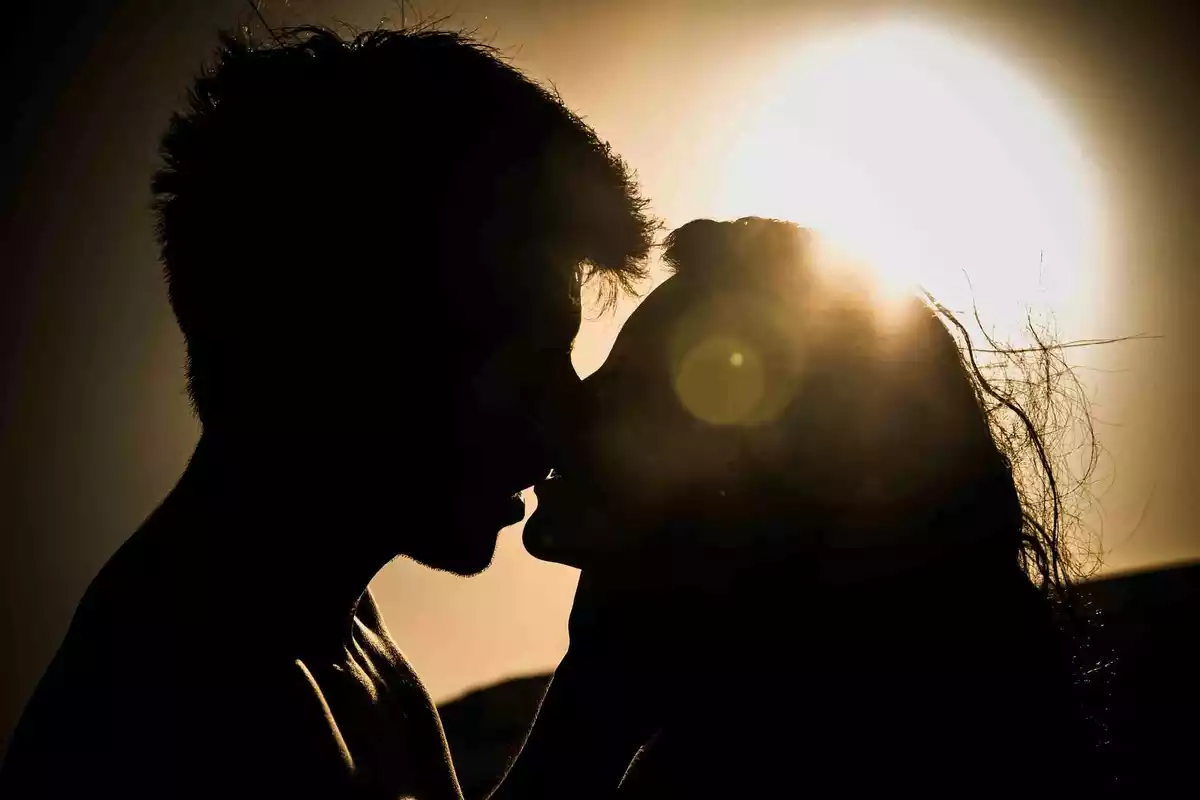 Couple kissing with a backlit sunset