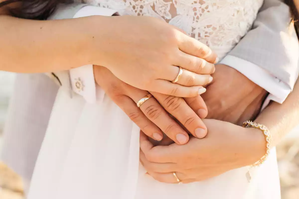 Two intertwined hands holding an engagement ring