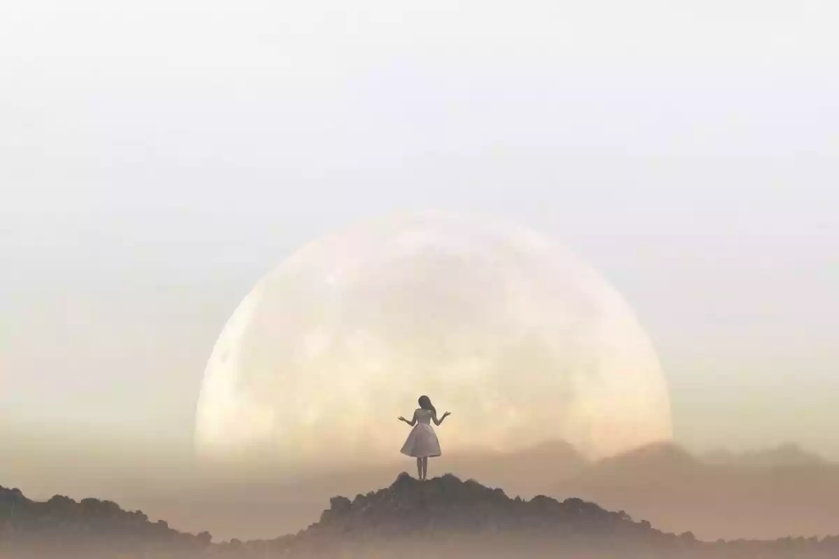 Woman on top of a mountain in front of the moon