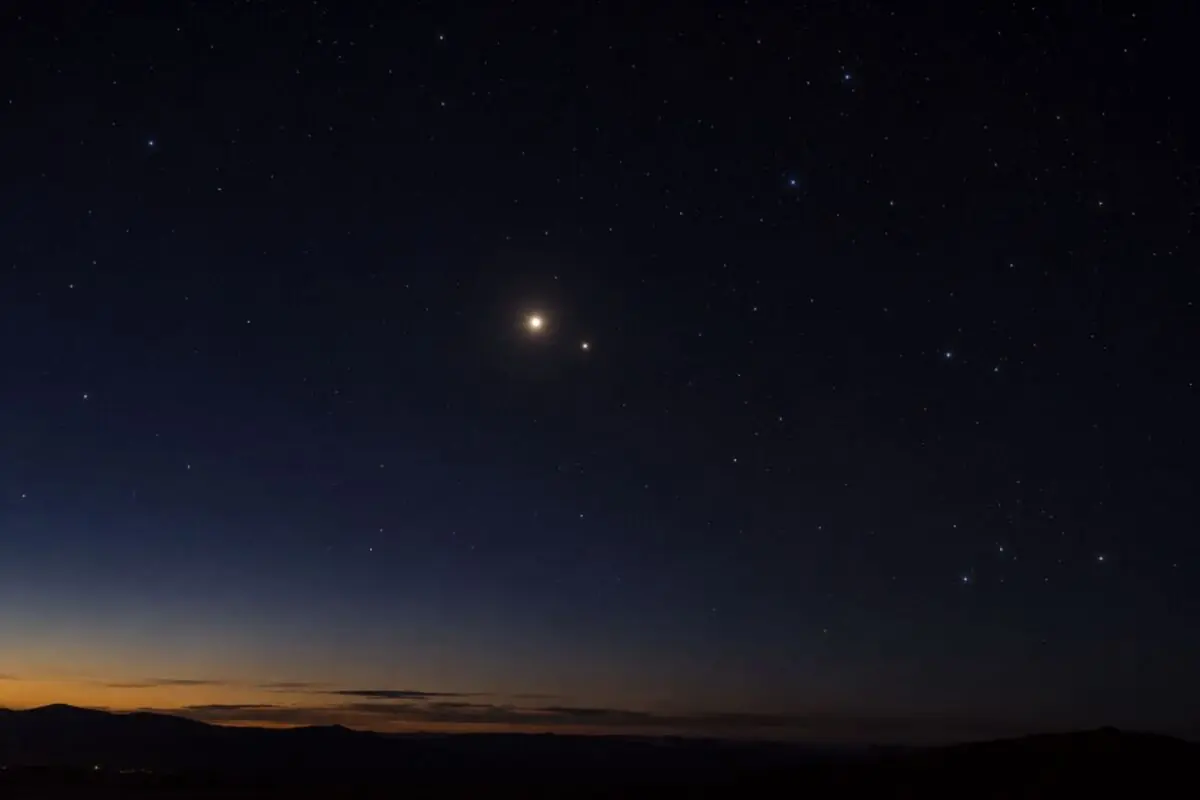 Night sky with two very bright planets above the horizon at dusk and a landscape of dark mountains. Night sky with two very bright planets above the horizon at dusk and a landscape of dark mountains.