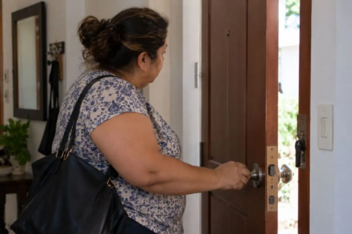 Woman with a handbag opening the front door of a house from the inside. Woman with a handbag opening the front door of a house from the inside.